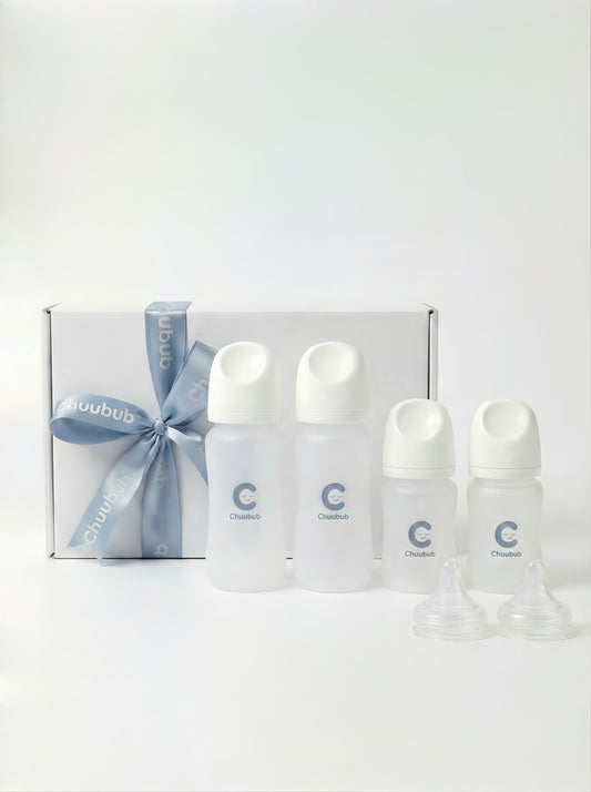 Set of baby bottles with a blue ribbon  tied over a white box against a white background